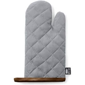 A grey kitchen mitten with a quilted design and a brown leather trim at the base. It features a logo.