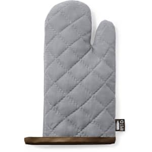 A grey quilted kitchen mitt with a brown textured grip and a small logo tag.