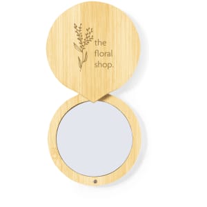 A bamboo pocket mirror with a floral design on the lid and a reflective surface inside.