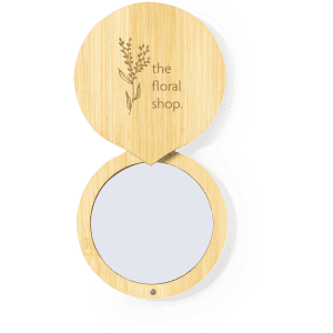 A wooden pocket mirror with a floral design on the lid, featuring a logo.