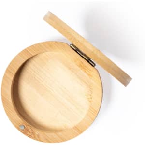 A round bamboo jewellery wrap with a hinged lid, featuring a smooth interior and a small logo.