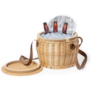 A woven thermal picnic basket with a brown strap, filled with ice and three brown drink bottles.