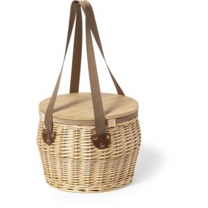 A woven wicker picnic basket with a wooden lid and brown straps. It features a logo on the side.