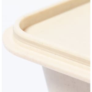 A close-up view of a cream-coloured lunch box with rounded edges and a smooth texture, featuring a logo.
