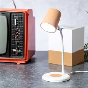A white multifunction lamp with a cork shade, beside a retro orange television, on a textured surface.