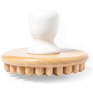 A wooden massager with a white handle and rounded base featuring protruding spikes for massage therapy.
