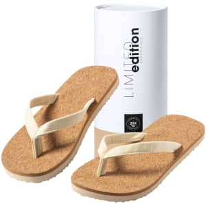 A pair of beige thongs with a cork sole, placed beside a cylindrical white box featuring a logo.