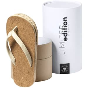 A pair of beige Yassir flip flops beside a white cylindrical packaging with a branding logo.
