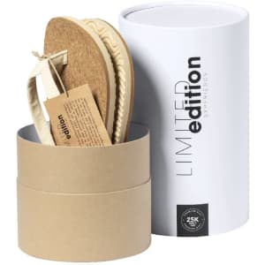 A pair of beige Yassir flip flops inside a cylindrical white box with a limited edition label.