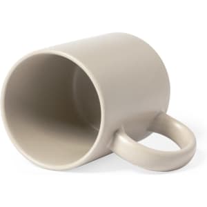 A beige coffee mug with a curved handle, positioned on its side and featuring a smooth finish.