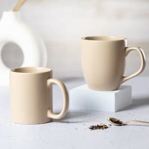 A coffee mug set in a soft beige colour, featuring a smooth finish and a minimalist design. One mug on a stand.