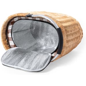 A woven wicker picnic basket in brown with a metallic silver insulated interior and a black handle.