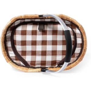 A thermal picnic basket with a checkered brown and white lining and a sturdy handle. It features a natural woven exterior.