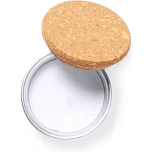 A round candle with a silver container and a cork lid, showcasing a smooth white wax interior.