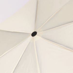 A cream umbrella with a central black button, displaying a smooth canopy and structured ribs.