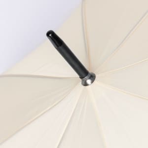 A cream umbrella featuring a black handle and metallic shaft. It has a simple, elegant design.