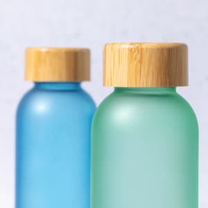A drink bottle in green and a drink bottle in blue, both featuring bamboo lids.