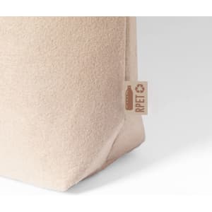 A light beige tote bag with a textured surface, featuring a small logo tag.
