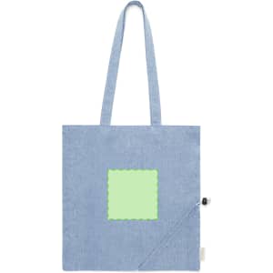A foldable bag in light blue with a green square patch and a small pouch for storage. Features shoulder straps and a logo.