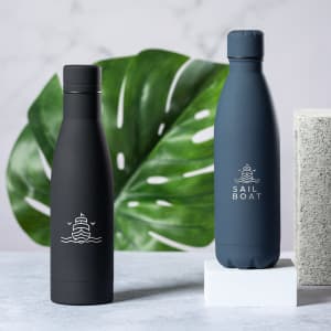 A drink bottle set featuring a matte black bottle and a navy blue bottle, both with logos, against a leafy background.