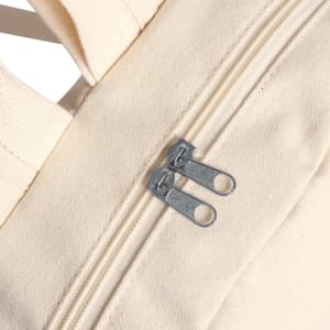 A cream-coloured backpack featuring a zipper with dual pulls and a textured fabric surface.