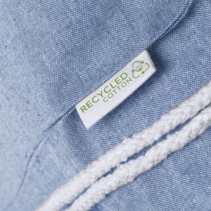 A blue drawstring bag made of recycled cotton, featuring a white rope drawstring and a label indicating its material.