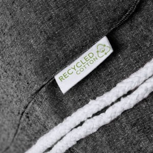 A close-up of a grey drawstring bag made from recycled cotton, featuring a white rope and a tag.
