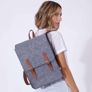 A grey backpack with brown straps worn by a model, featuring a simple design and branding.
