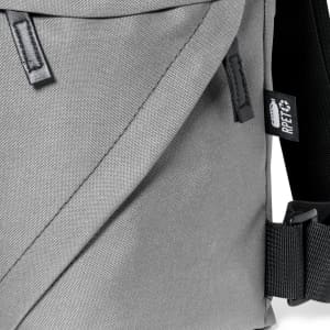 A grey backpack with a textured fabric, featuring a strap and branding label.