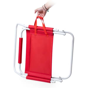 A red folding chair with white metal frame and orange handles being held. Includes a logo on the fabric.