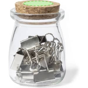 A glass jar with a cork lid filled with silver binder clips. The jar has a green decorative label.
