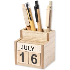 A wooden pencil holder featuring a perpetual calendar with blocks displaying July and the number 16, filled with various pens.