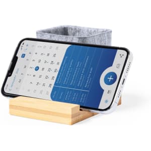 A grey felt pencil holder sits on a wooden stand, supporting a smartphone displaying a calendar.