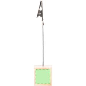 A metal clip attached to a silver rod, mounted on a wooden base with a green square on it.