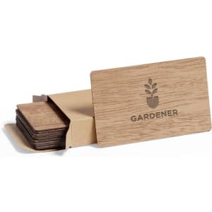 A wooden business card set in a kraft paper sleeve, featuring a plant logo. The cards are in natural wood tones.