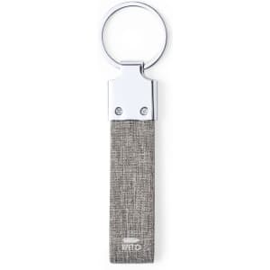 A grey fabric keyring with a silver metal attachment. Features a logo on the fabric.