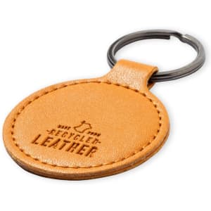 A round, tan keyring made of recycled leather with a metal keyring attachment. It features a subtle embossed design.