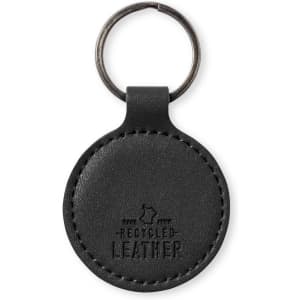 A round black keyring made of recycled leather with a metal ring for attachment. Features branding on the surface.