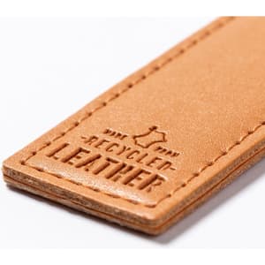 A tan leather keyring made from recycled materials, featuring embossed text and a smooth finish.