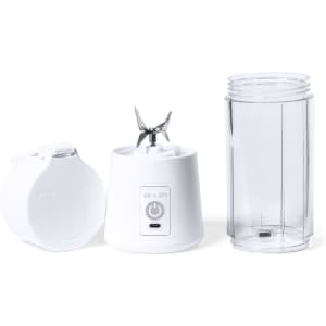 A white blender base with a transparent blending jar, featuring a blade and an on/off button. It has a logo.