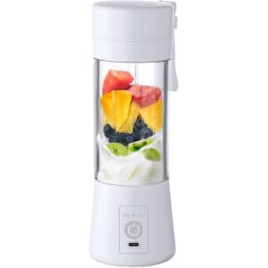 A white portable blender with assorted fruits and a logo at the base. The container is transparent, showcasing the ingredients.