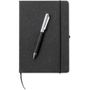 A black notebook with a pen rests on top, featuring an elastic band and a ribbon bookmark.
