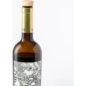 A drink bottle made of amber glass with a wooden cork cap, featuring intricate black and white designs on the label.