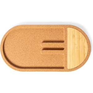 A cork and bamboo organiser with a curved oval shape, featuring compartments for charging devices.