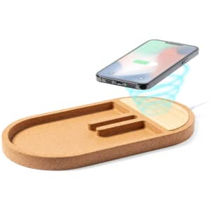 A cork wireless charger with a sleek oval design, featuring slots for organising phones and accessories.