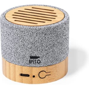 A round, portable speaker with a grey fabric top and a bamboo base, featuring a logo on the front.