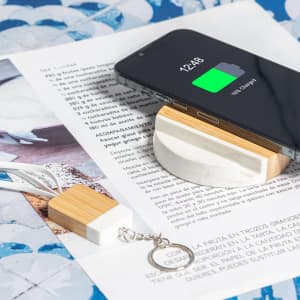 A charging cable with a bamboo and marble design, positioned next to a smartphone on a patterned surface.