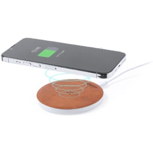 A wireless charger with a brown wooden surface and a white base, featuring a smartphone indicating charging status above it.