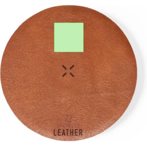 A wireless charger with a round brown leather surface and a small green square in the centre. It features a logo.