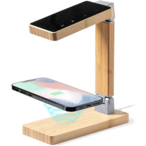 A multifunction alarm clock with a wireless phone charger, featuring a bamboo base and a sleek black top.